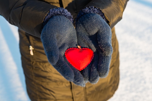 Woman hands in blue gloves holding red heart winter outdoors valentines day time