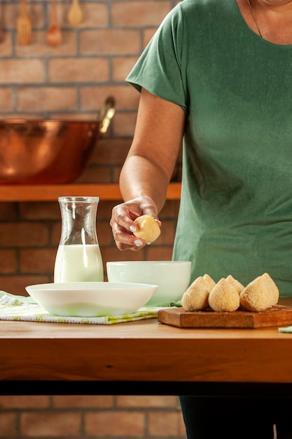 여자 손 빵 부스러기와 나무 식탁에 브라질 크로켓 coxinha de frango 빵