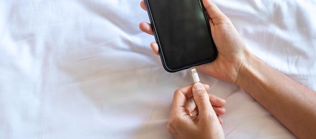 Woman hands charging battery in mobile smart phone in the\
bedroom at home technology multiple sharing and lifestyle\
concepts