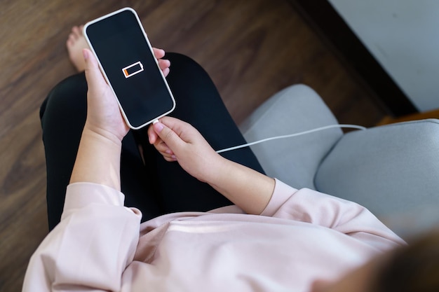 Woman hands Charging mobile phone battery with low battery plugging a charger in a smart phone with energy bank powerbank power charger Modern lifestyle energy technology concept