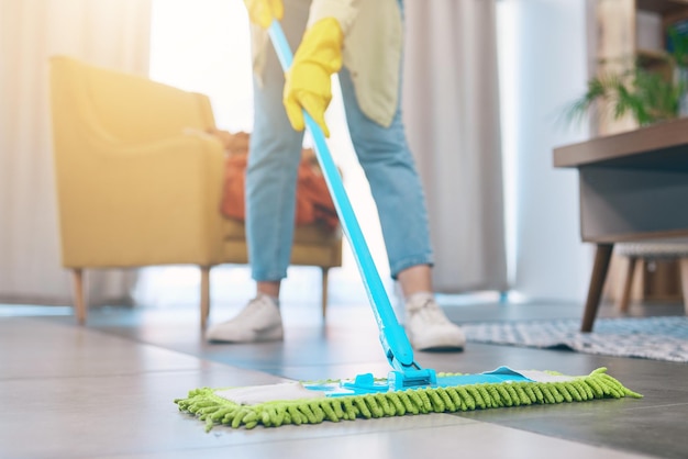 女性の手と、自宅で衛生的な細菌や細菌を除去するためにリビングルームでモップで床を掃除する女性の家政婦または家事代行のメイド、家の消毒のための汚れやほこり