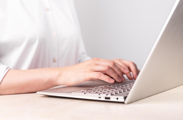 Женщина руками крупным планом печатает на клавиатуре ноутбука Использование компьютера для работы Работа офис-менеджера Женщина сидит за столом