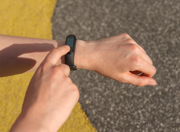 Primo piano delle mani della donna con braccialetto fitness tracker per il monitoraggio del numero di passi o della frequenza cardiaca durante la corsa o lo sport concetto di assistenza sanitaria