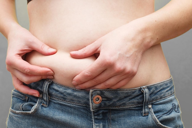 Woman hands compresses the fat on her belly