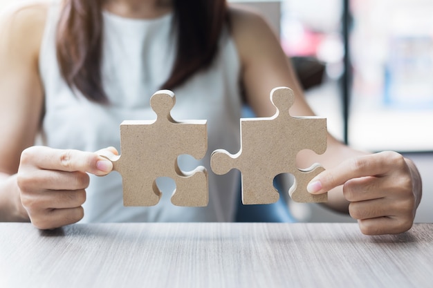 Foto mani della donna che collegano puzzle delle coppie sopra la tavola