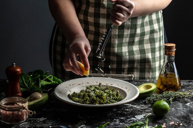 Woman hands cooking Penne pasta and adding cheese parmesan in dish