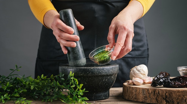 Woman hands cooking pouring parsley into the mortar