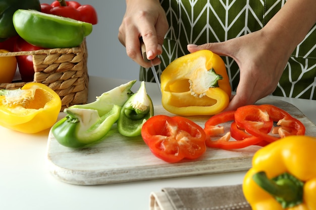 Woman hands cut bell pepper on white board