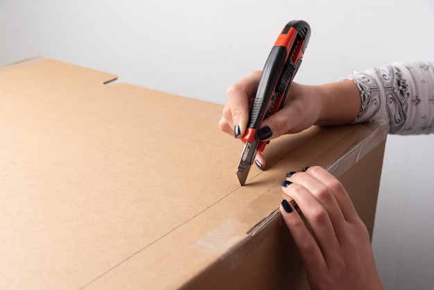 Photo woman hands cutting carton by marked line drawn on box with copy space for adding explanation of tutorial or guide through how to