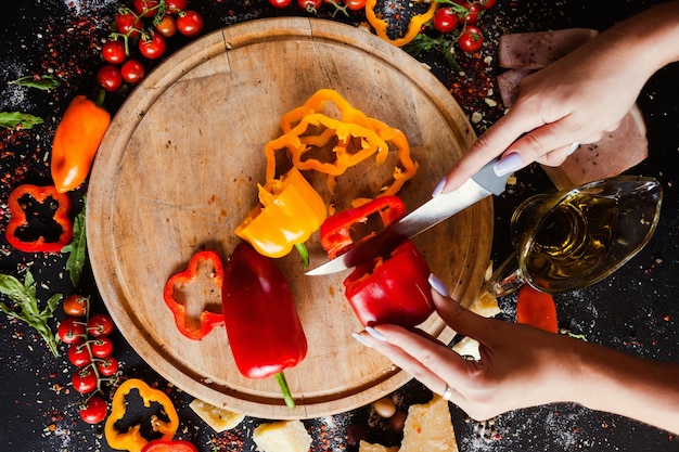 Mani della donna che tagliano i peperoni dolci cibo biologico vegetariano. preparazione del concetto di insalata sana