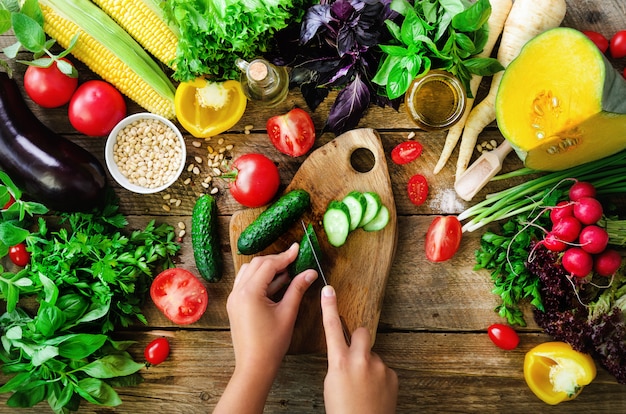 Photo woman hands cutting vegetables on wooden background. vegetables cooking ingredients