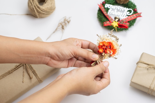 Woman hands decorating Christmas craft handmade presents with dried flower 