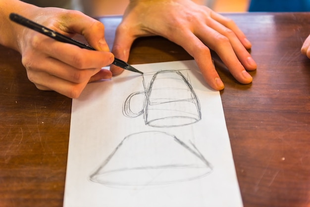 Woman hands drawing a draft of a future clay cup for pottering