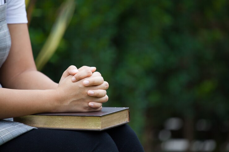Photo 自然の緑の背景に信仰の概念のために聖書の祈りで折りたたまれた女性の手