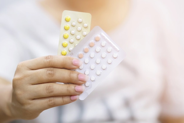 Woman hands give birth control pills in hand. Contraception reduces childbirth and pregnancy concept.