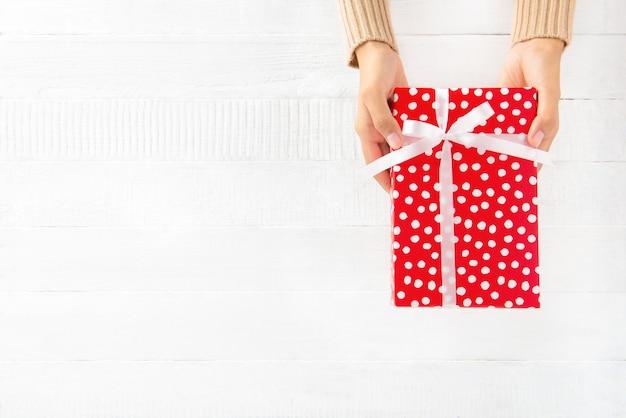 Woman hands giving red gift box 