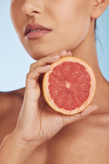 Woman hands and grapefruit for vitamin C skincare or diet against a blue studio background Closeup of female person with organic citrus fruit for natural nutrition dermatology or healthy wellness