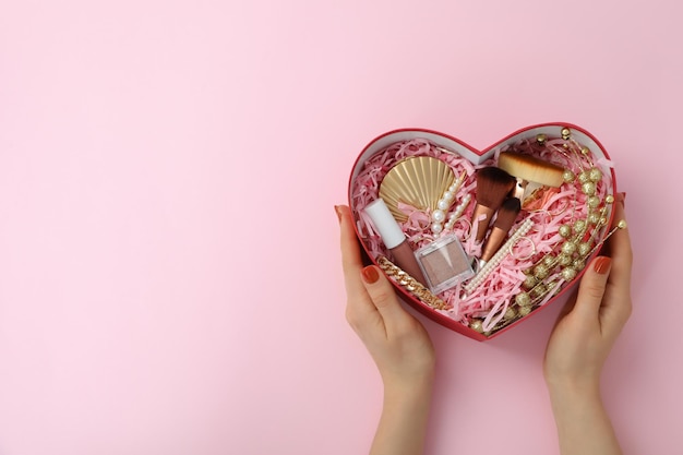 Woman hands hold female gift box on pink background