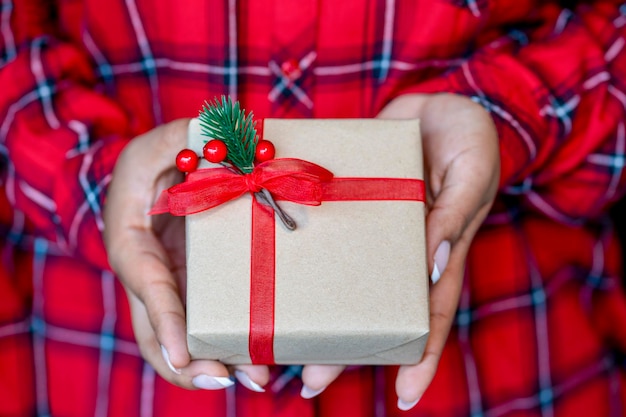 Woman hands hold gift box wrapped in paper with ribbon