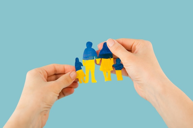 Woman hands hold a papercut family painted in the national colors of ukraine