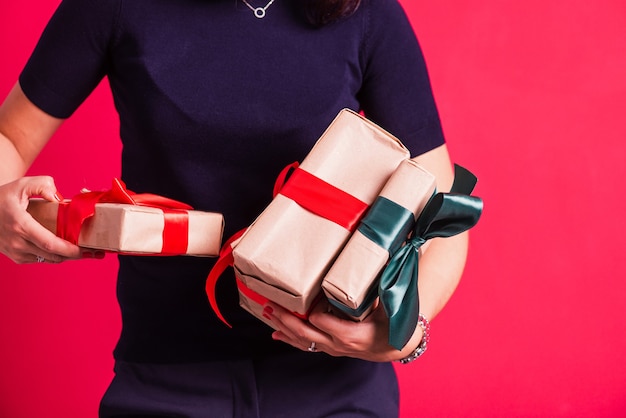 Woman hands hold three presents at studio pink background