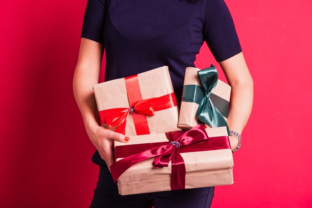 Woman hands hold three presents at studio pink background