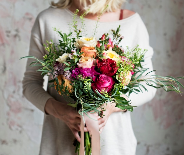 Mani della donna che tengono il mazzo di bei fiori