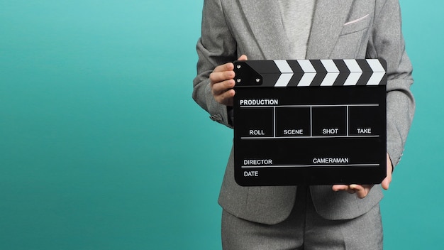 Woman  hands holding black clapper board or clapperboard or movie slate and wear grey suit  on green...