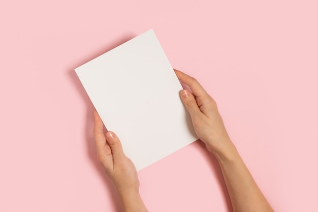 Woman hands holding blank card on pink table