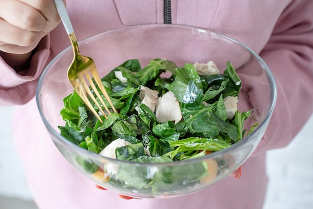 Woman hands holding bowl of healthy salad with spinach and peach