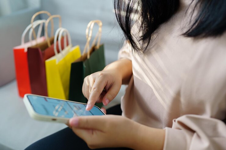 Photo スマートフォンを使って携帯電話を握っている女性の手ショッピングバッグの販売買い物バッグのショッピングモールでの消費主義ライフスタイルコンセプト