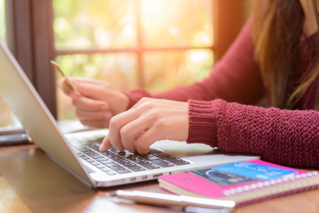 Woman hands holding a credit card and using laptop computer for online shopping