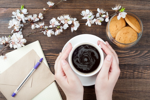 木製の背景にコーヒーのカップを保持している女性手