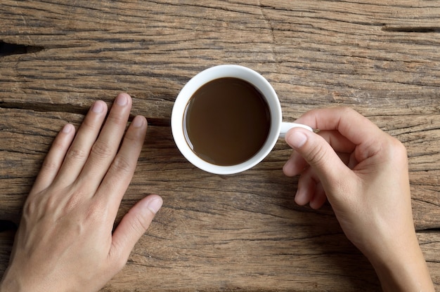 woman hands holding cup of coffee on wooden table background