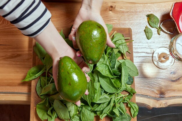 Woman hands holding fresh ripe organic green avocado choose best for cooking guacamole