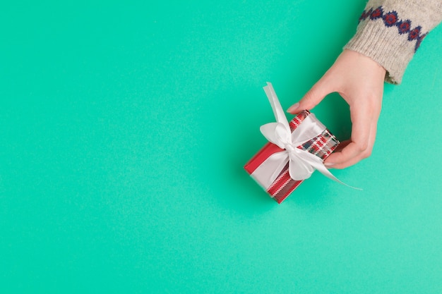 Woman hands holding gift box on green