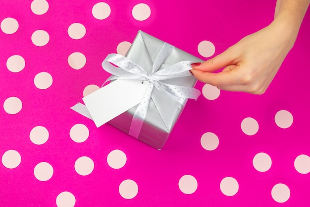 Foto la donna passa il contenitore di regalo della tenuta su fondo rosa