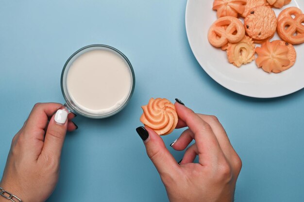 ミルクとデンマークのバタークッキーのガラスを保持している女性の手