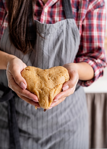 Woman hands holding heart shaped dough