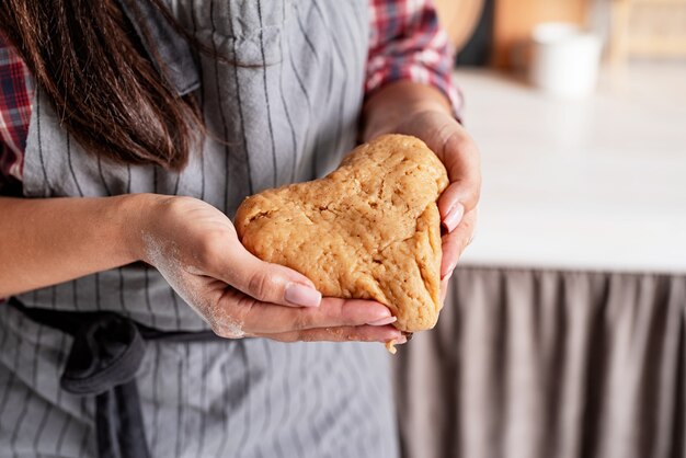 Photo woman hands holding heart shaped dough