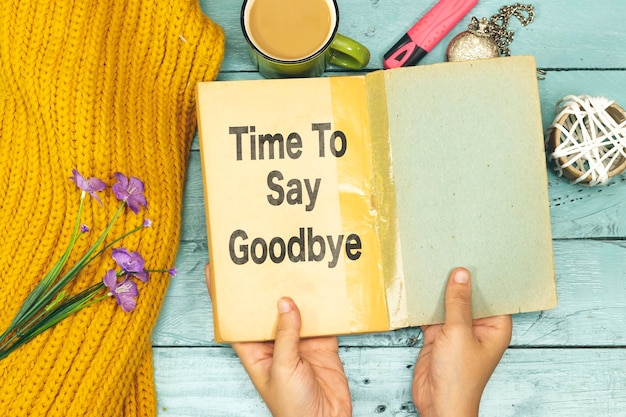 Woman hands holding an old book with time to say goodbye concept