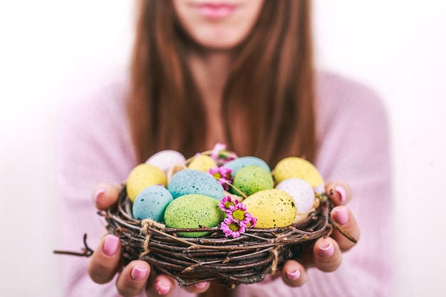 Woman hands holding painted easter egg in a small nest toned picture selective focus