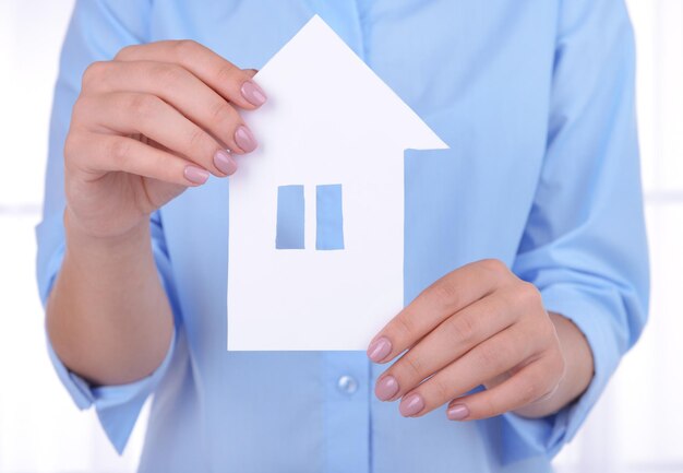 Woman hands holding paper house on light background
