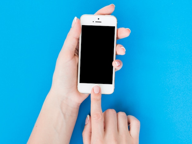 Woman hands holding smartphone on blue background