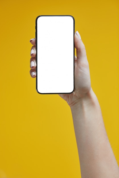 Woman hands holding smartphone on yellow .