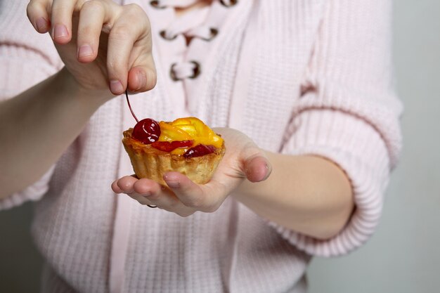 Woman hands holding tasty cupcake with berries and orange. Closeup shot