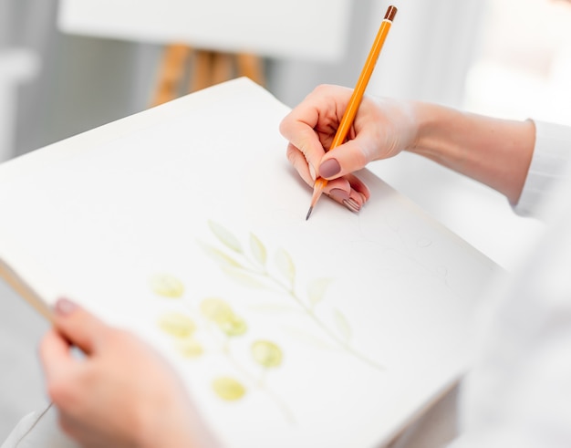 Foto mani della donna che tengono carta tela bianca e matita grafica e schizzo di disegno