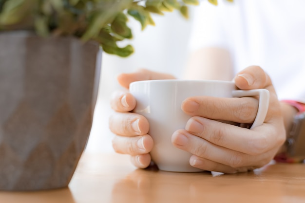 Woman hands holding white coffee cup