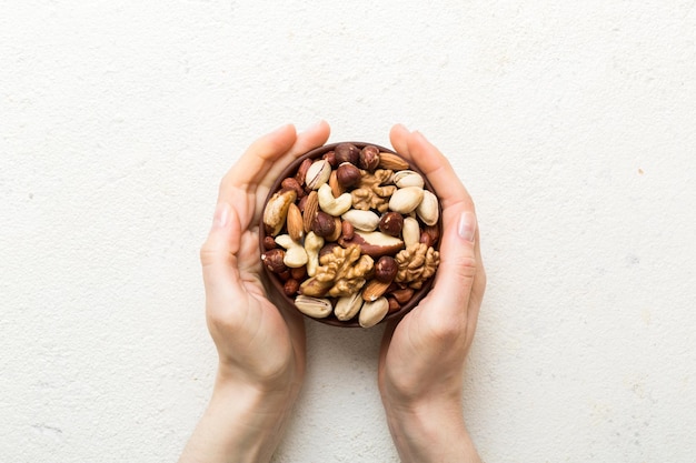 woman hands holding a wooden bowl with mixed nuts walnut pistachios almonds hazelnuts and cashews healthy food and snack vegetarian snacks of different nuts