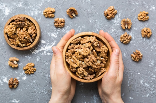 Woman hands holding a wooden bowl with walnut nuts Healthy food and snack Vegetarian snacks of different nuts